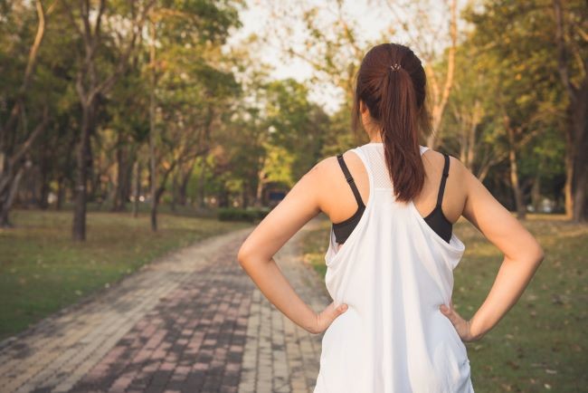 Woman looking down a long, winding road 